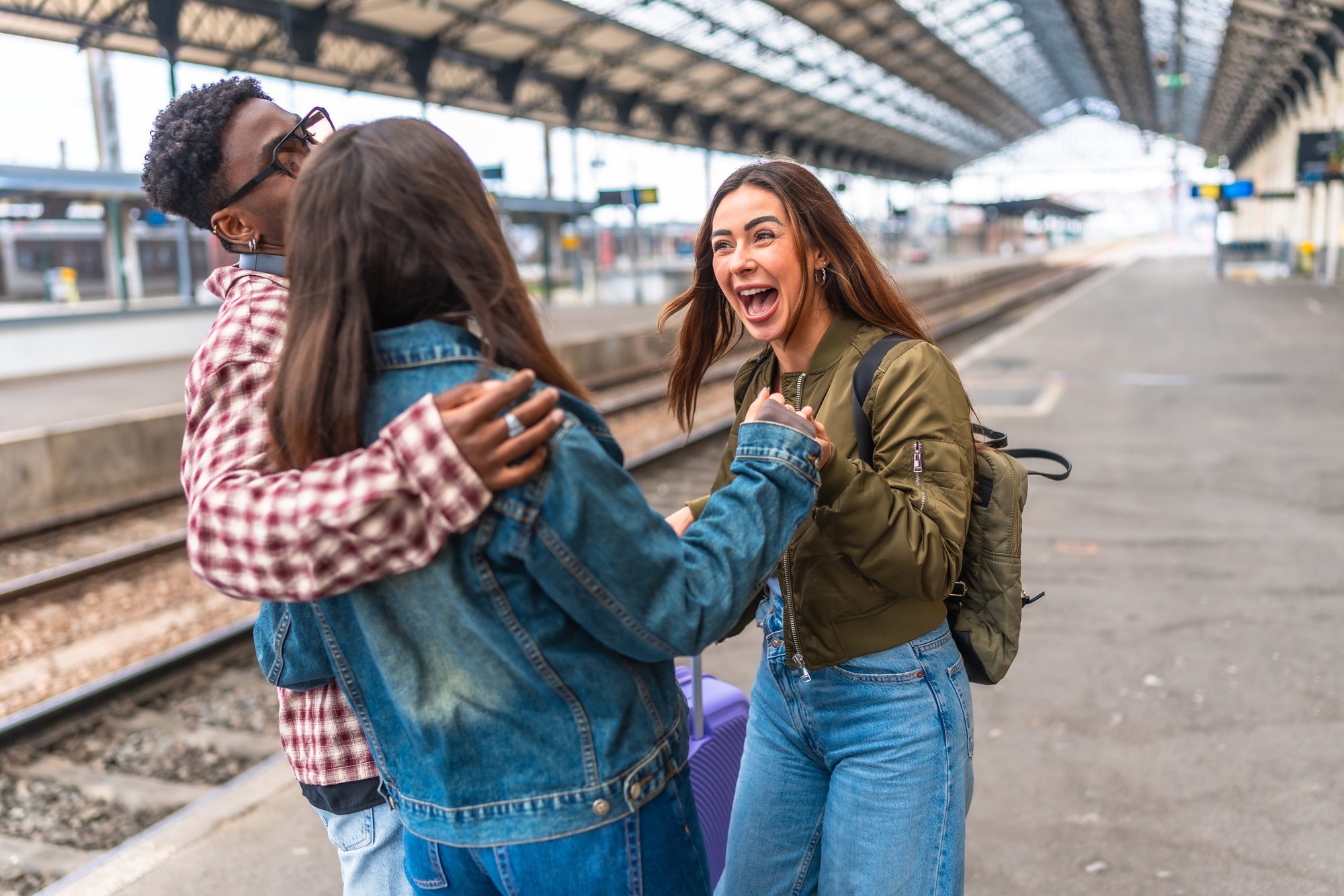 Happy friends meeting at train station embracing and smiling
