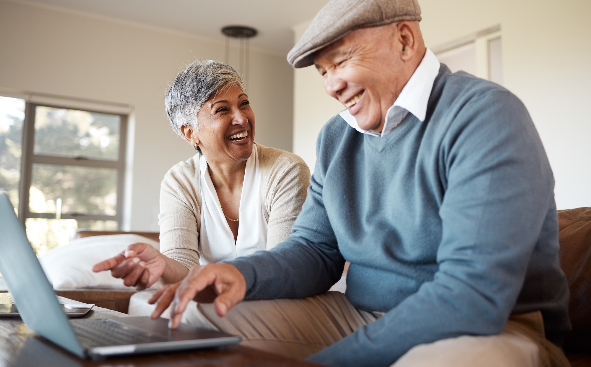 Happy, love and senior couple with a laptop on a sofa for subscription, search or sign up service a