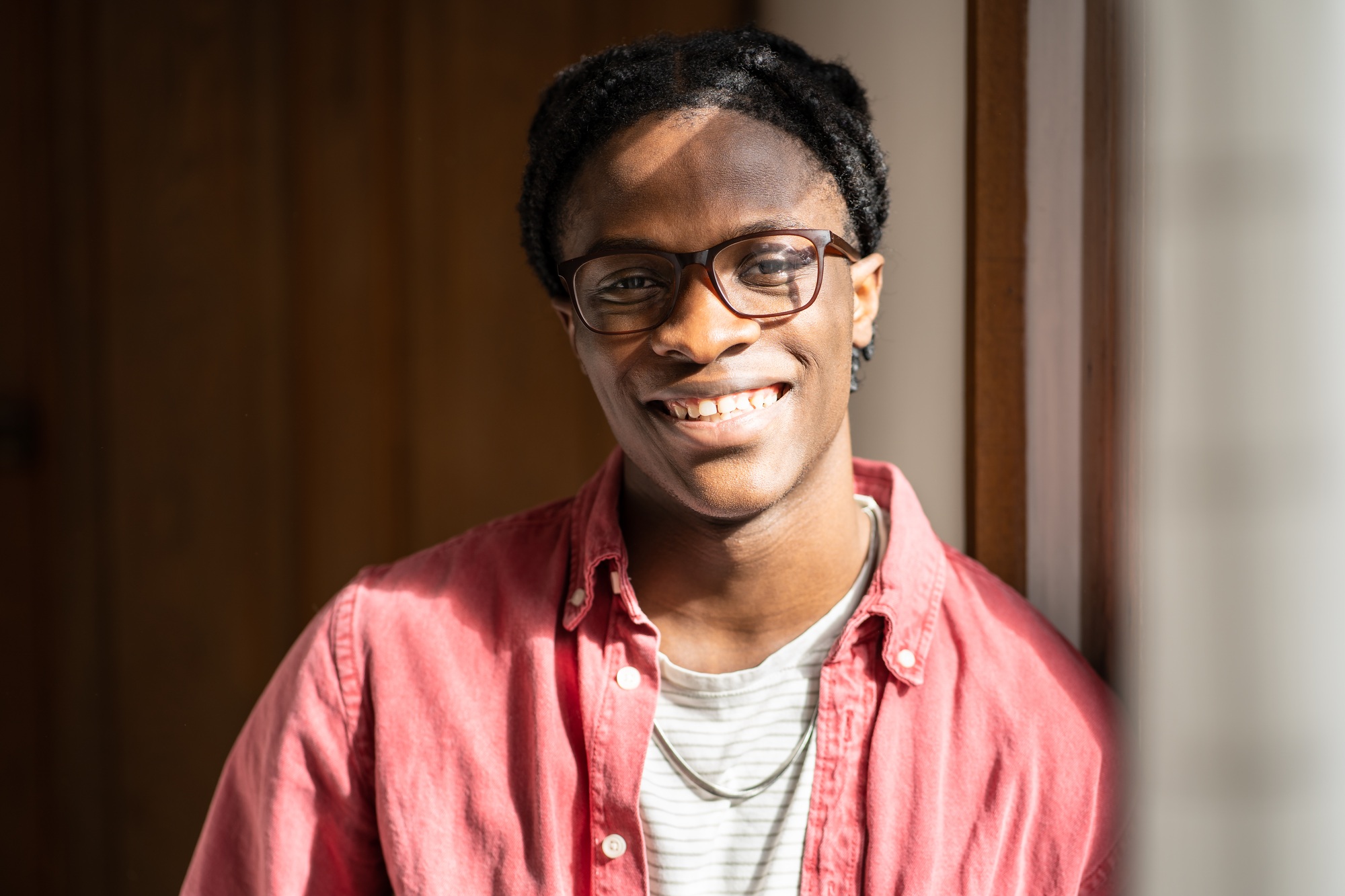 Happy optimistic young African American guy standing at home expressing positive emotions