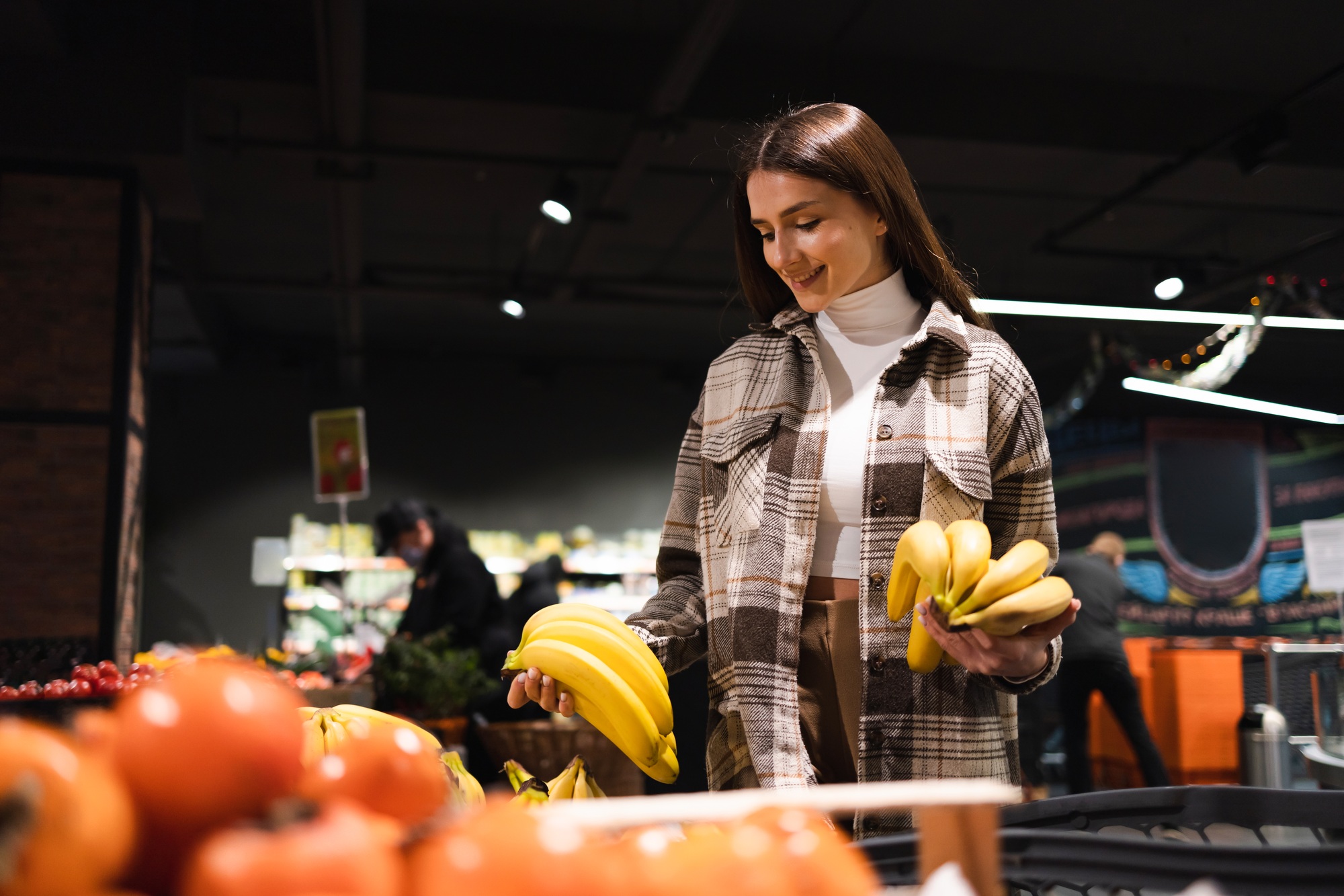 Happy woman chooses bananas in the supermarket. Grocery store customer portrait