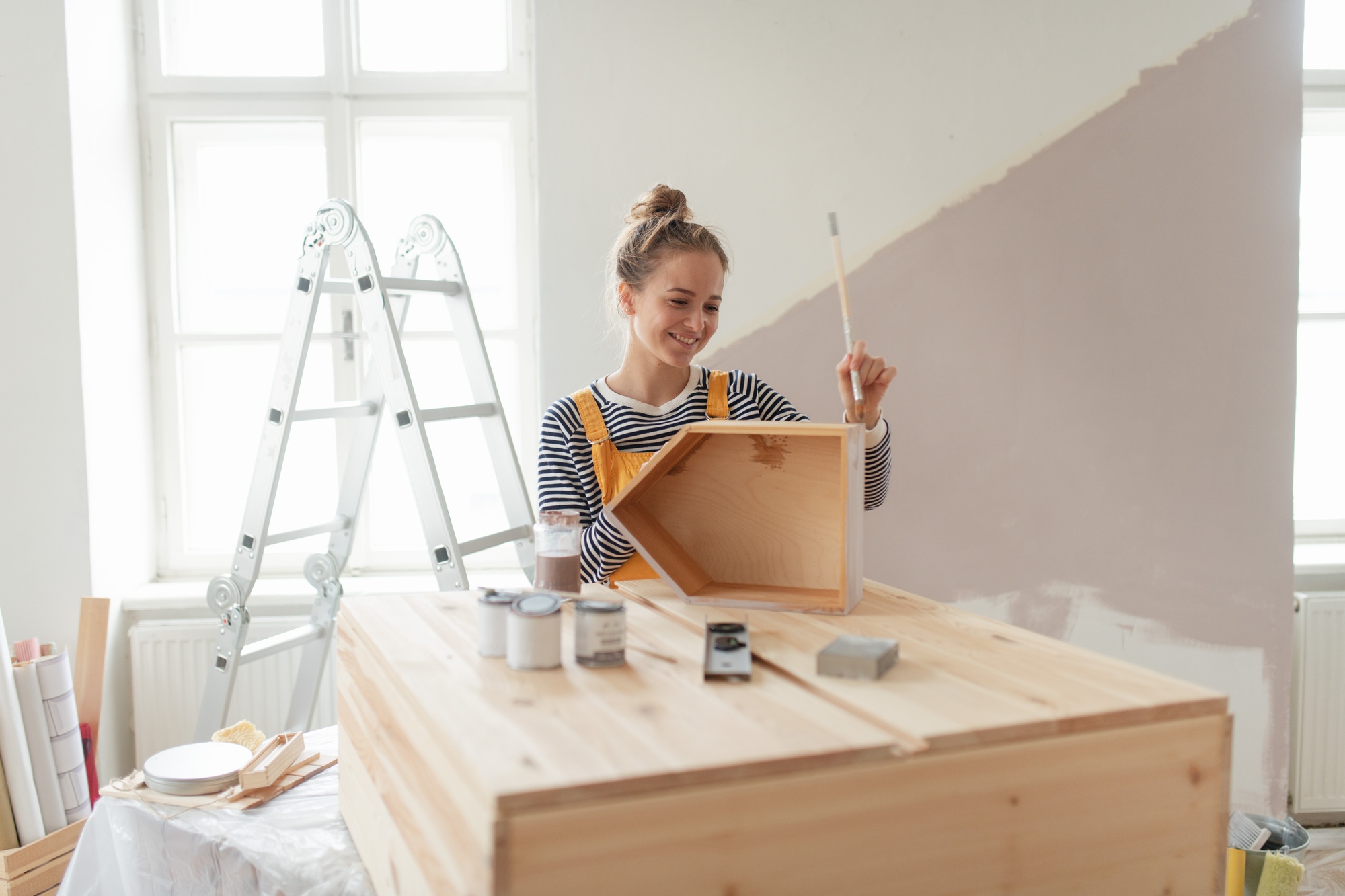 Happy young woman remaking shelf in her new flat. Concept of reusing materials and sustainable