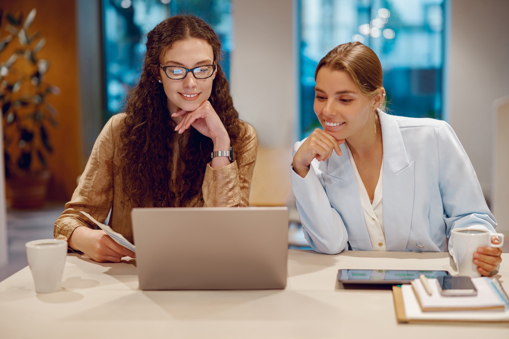 In a modern office, two professionals collaborate on a laptop to achieve their goals