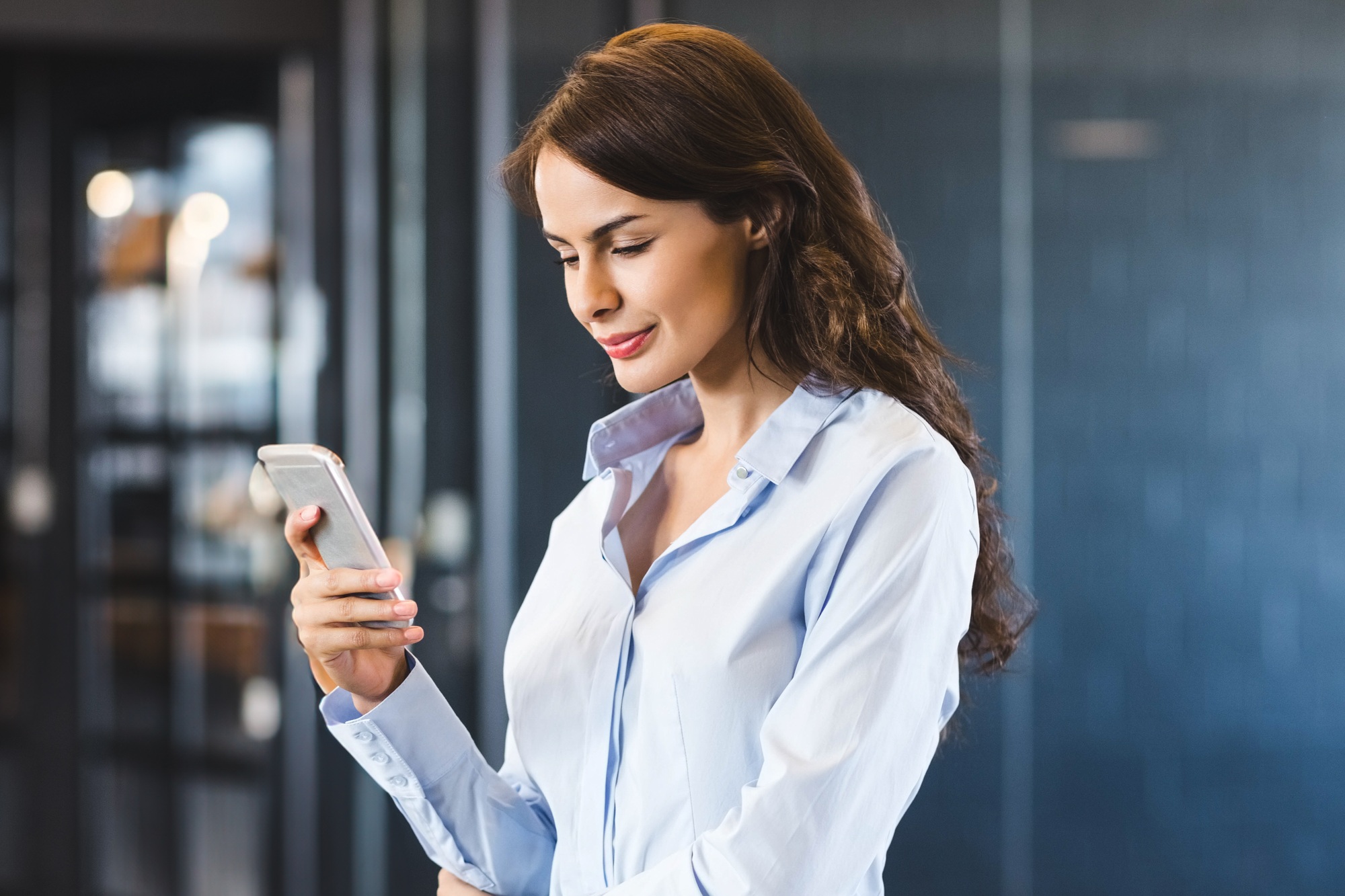 In modern office, businesswoman focusing on smartphone screen, working efficiently