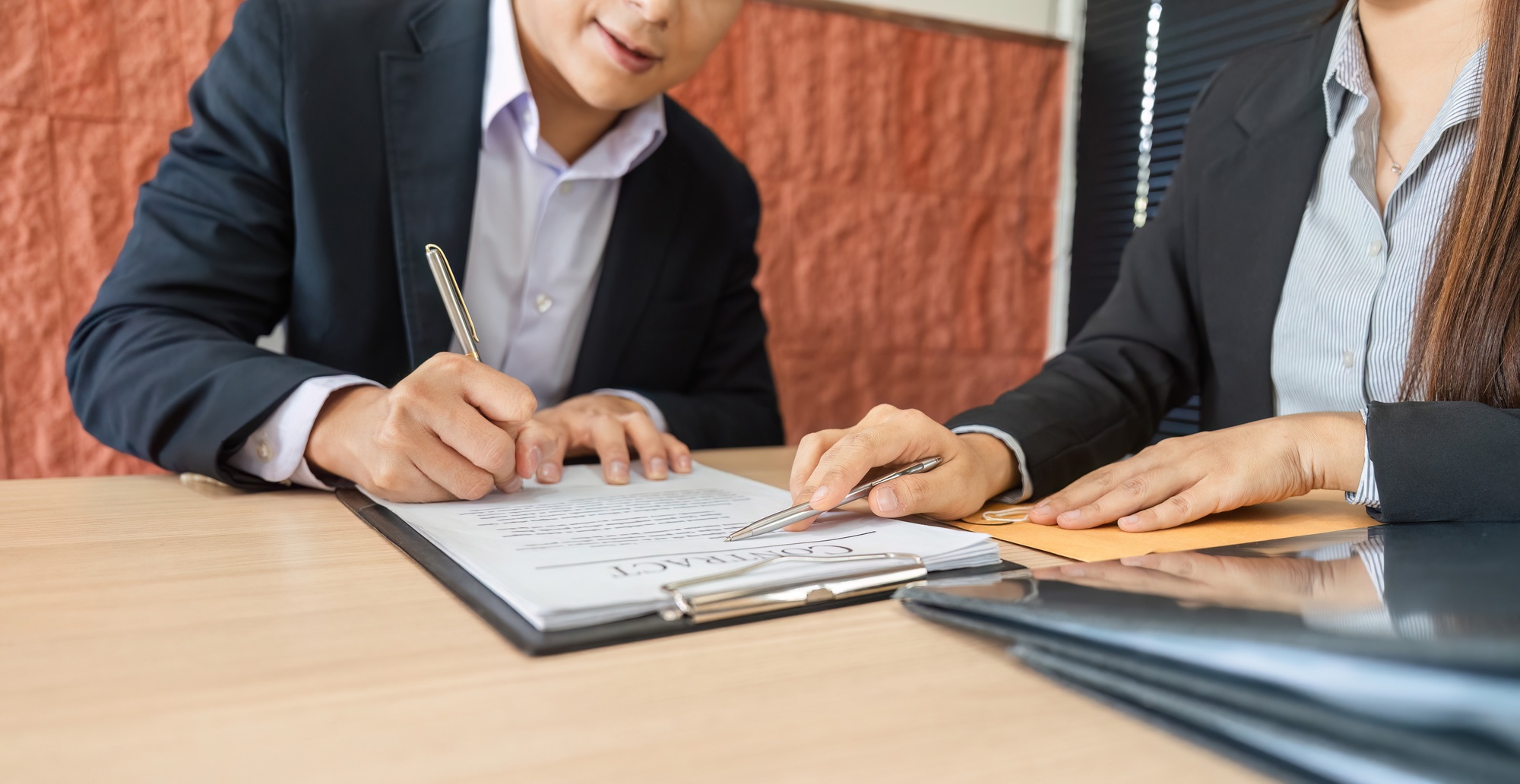 Individuals completing a contract signing process for a business deal.
