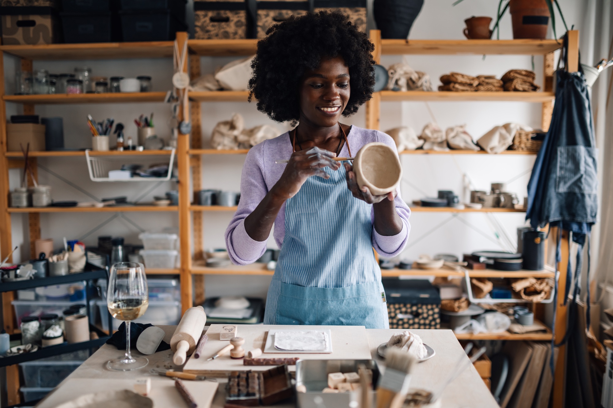 Interracial craftswoman decorating handcraft and having wine at pottery studio