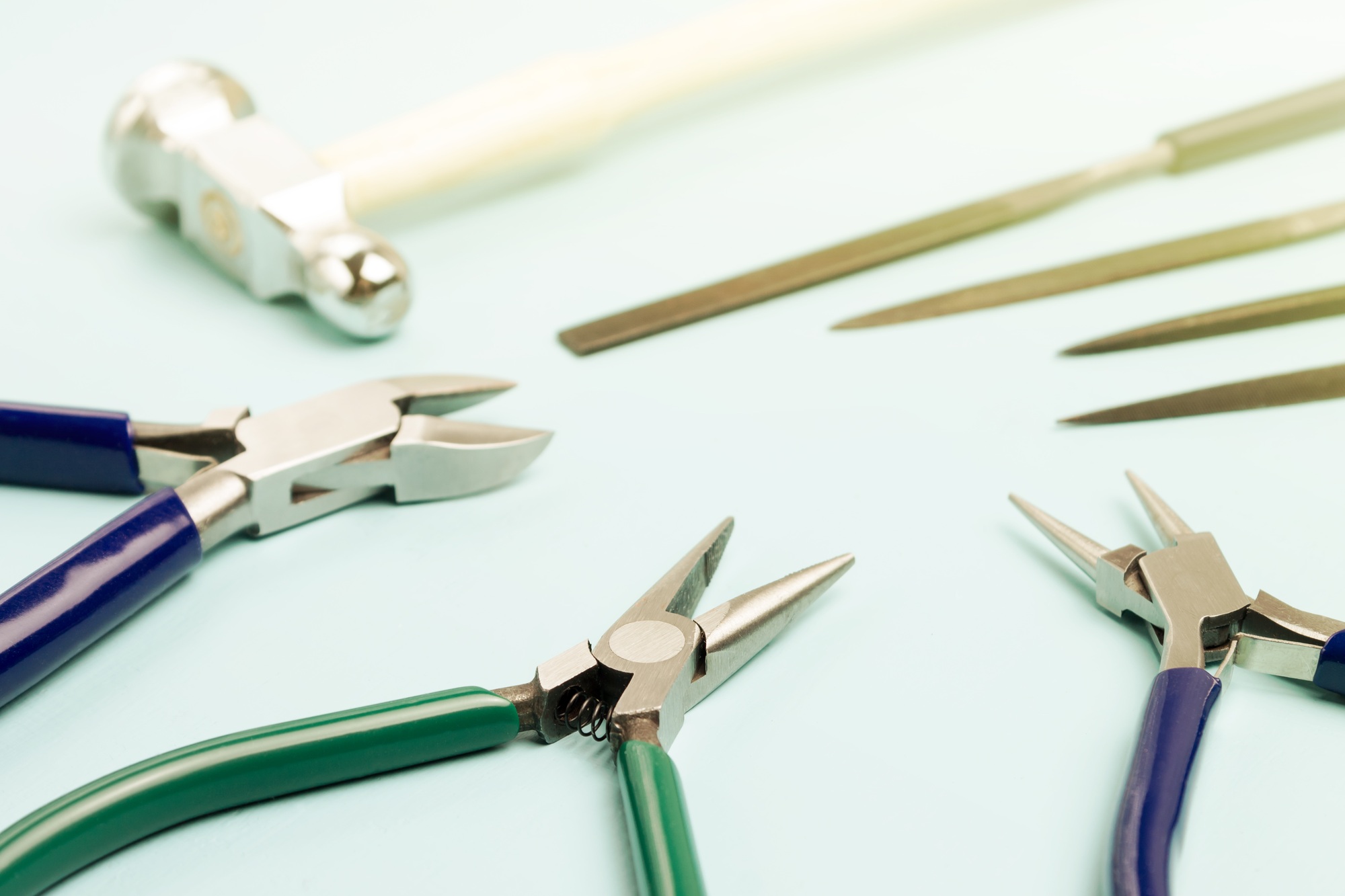 Jewelry tools. Pliers, hammer and files on a blue background