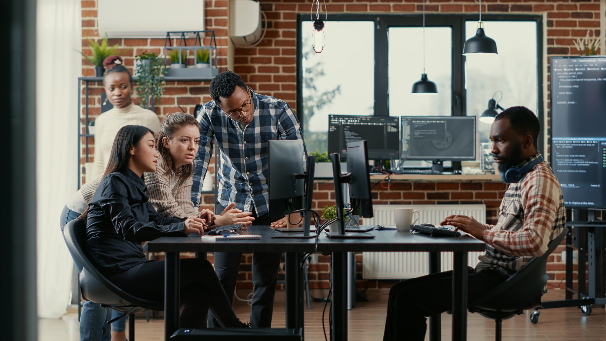 Junior developers collaborating on group project compiling algorithm asking senior programer for