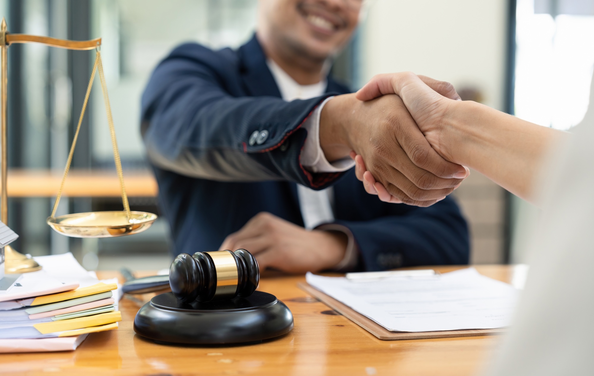 lawyer or attorneys shaking hand with client after consultation discussing a contract agreement
