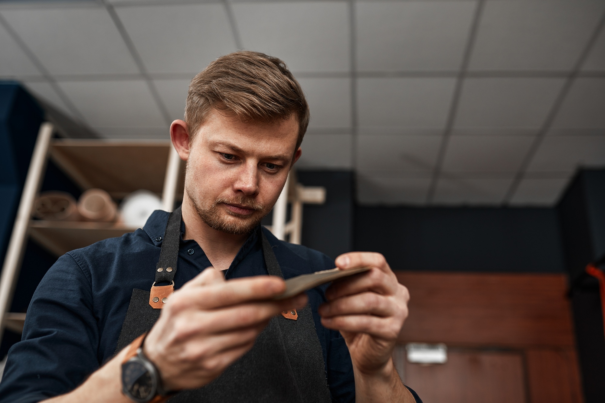 Leather craftsman checks a product in a workshop, small and medium-sized businesses, a family