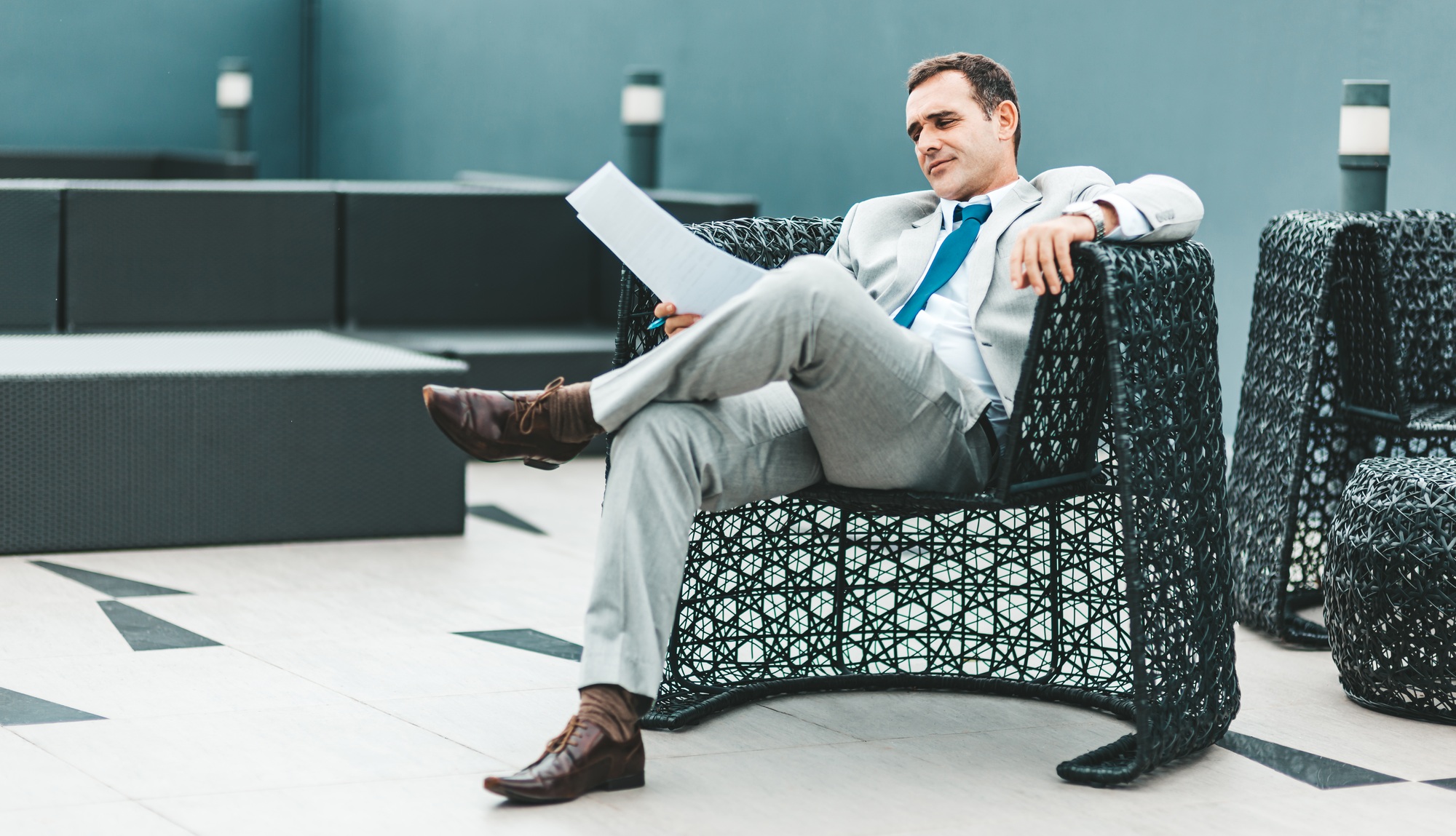 Make a decision. Businessman reading papers while sitting in an armchair.