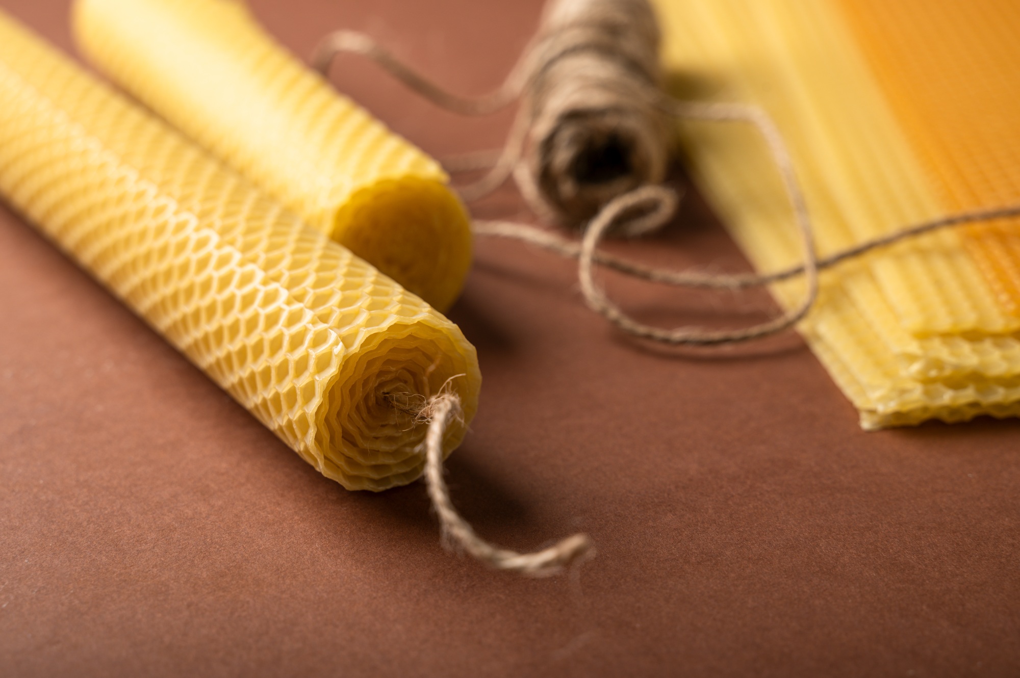 Making candle from Beeswax honeycomb sheet on brown background