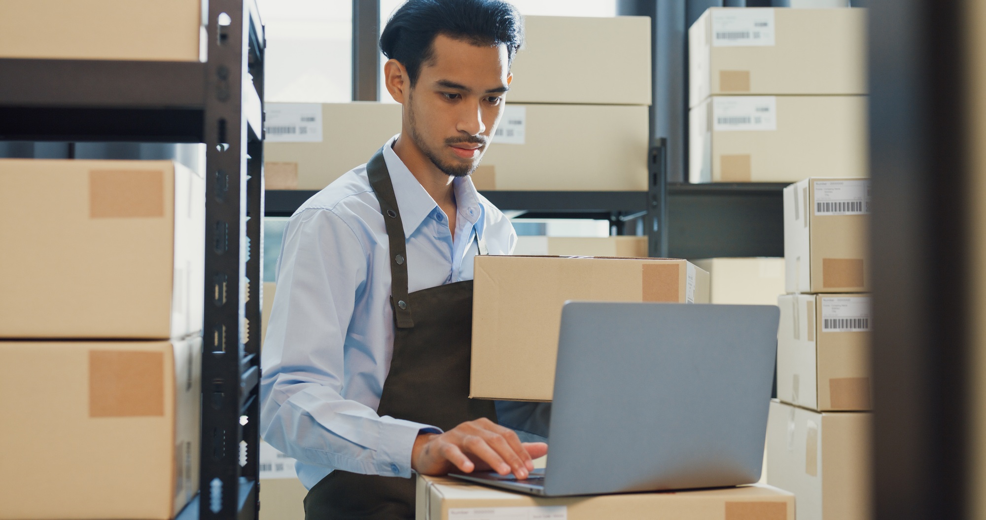 Man hold cardboard box use laptop computer check inventory online stock data.