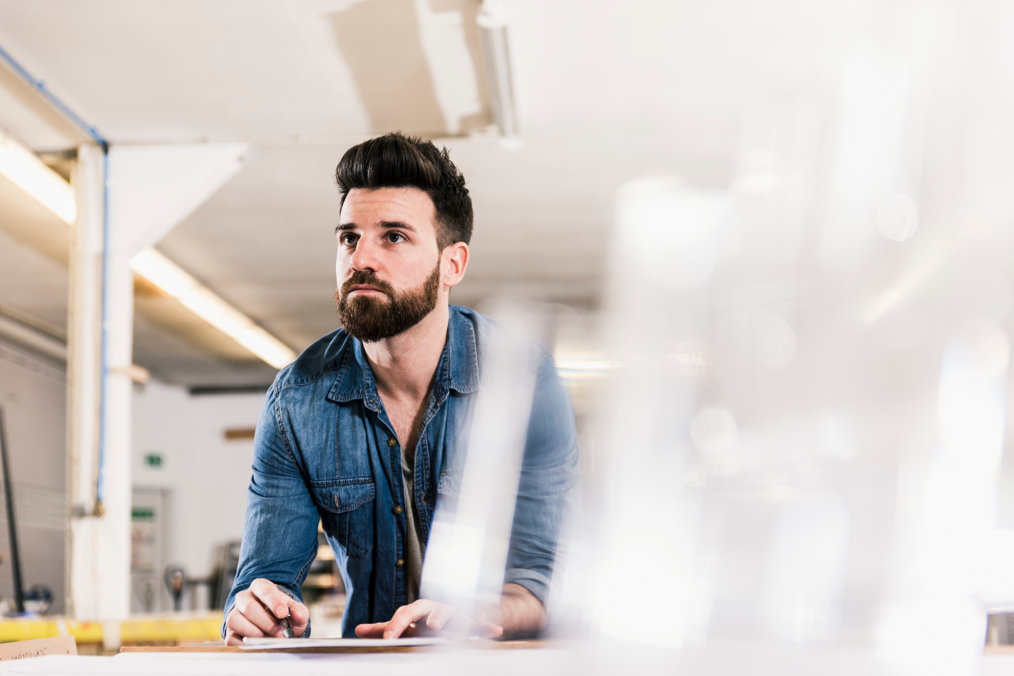 Man looking up from draft in workshop