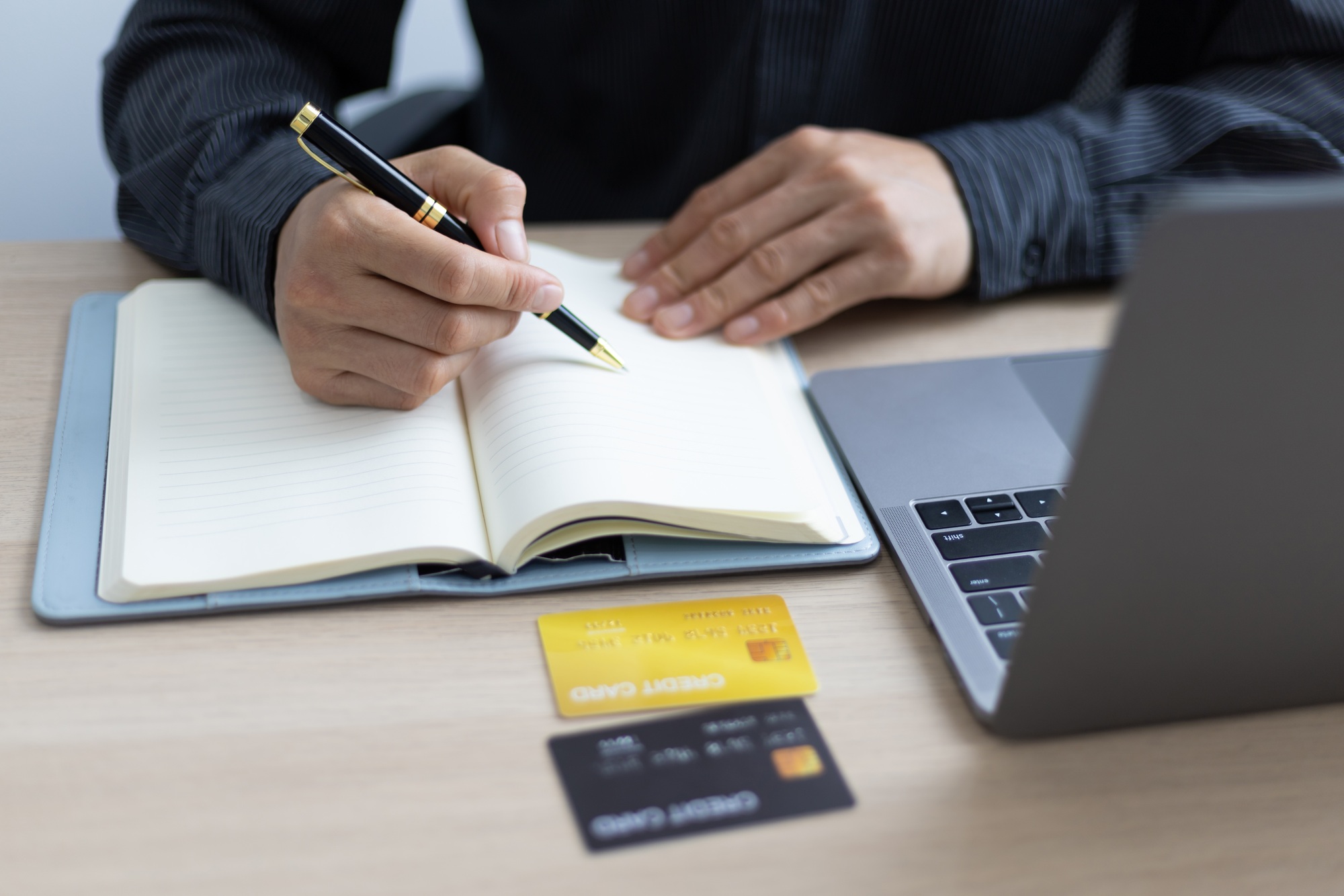 Man writing credit card expense record. Financial planning and cost reduction.