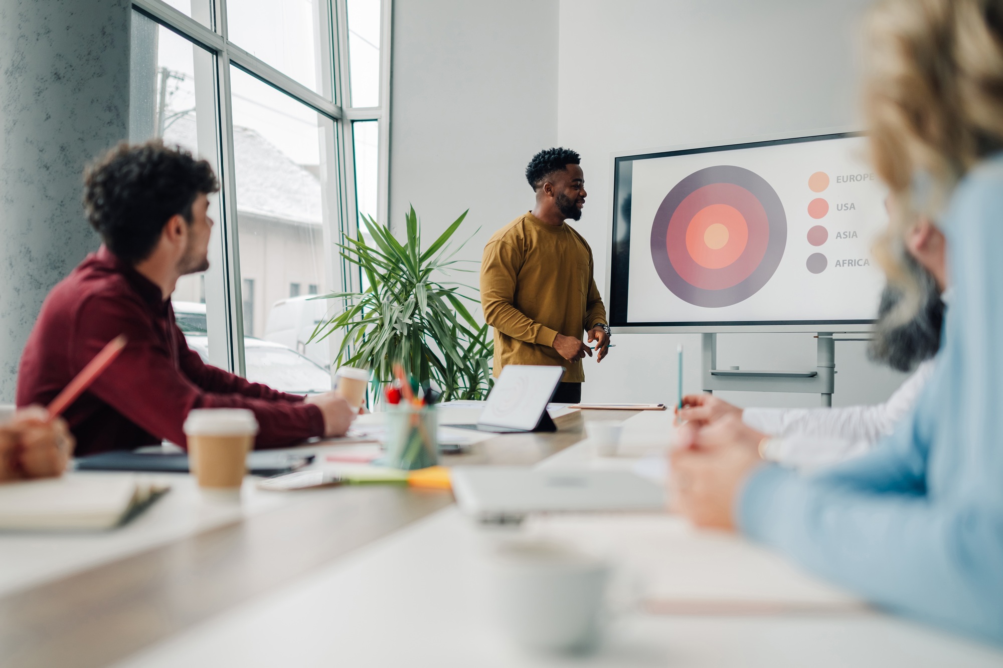 Marketing manager presenting sales data to colleagues in meeting room