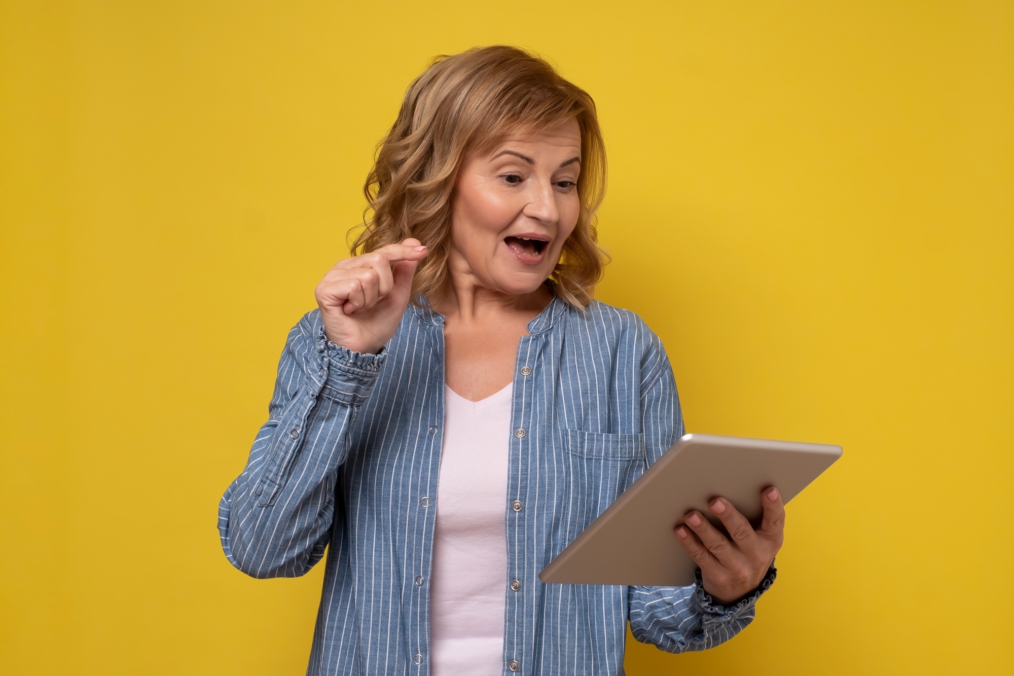 Mature attractive smiling woman using a tablet computer selecting goods in online shop