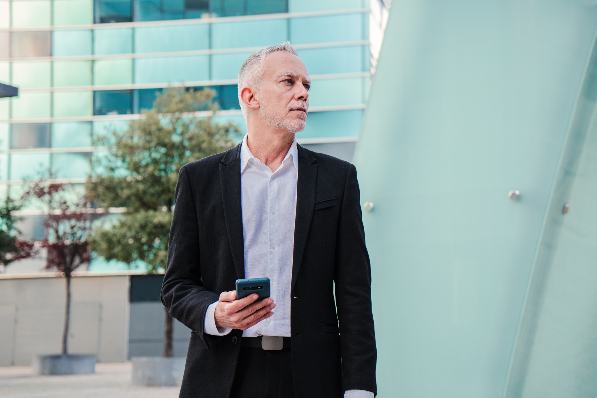 Mature business man using a cellphone at workplace. Handoseme middle aged executive male, lawyer