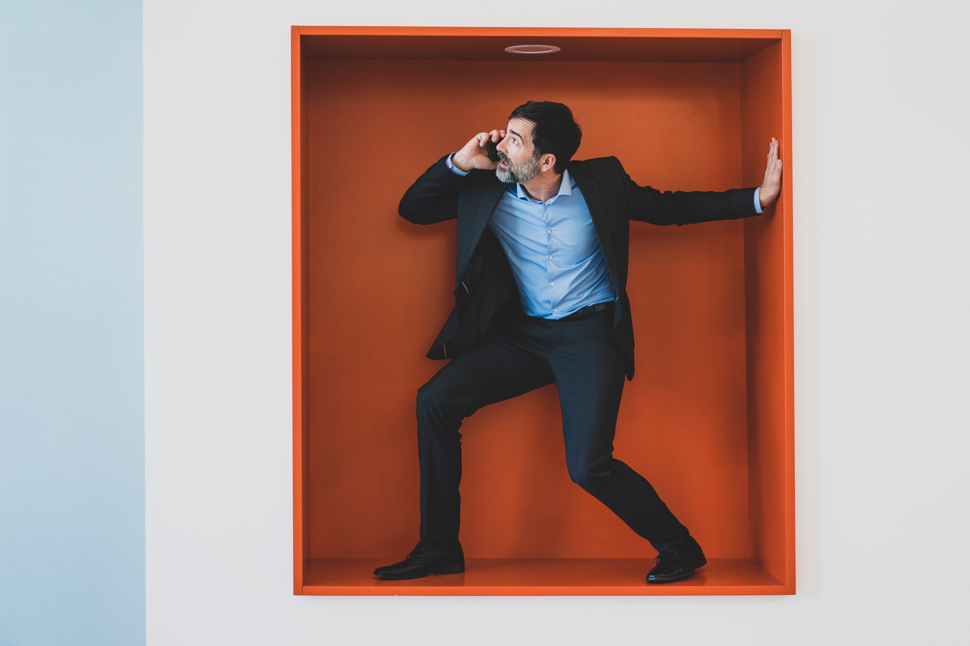 Mature businessman on cell phone caught in a niche