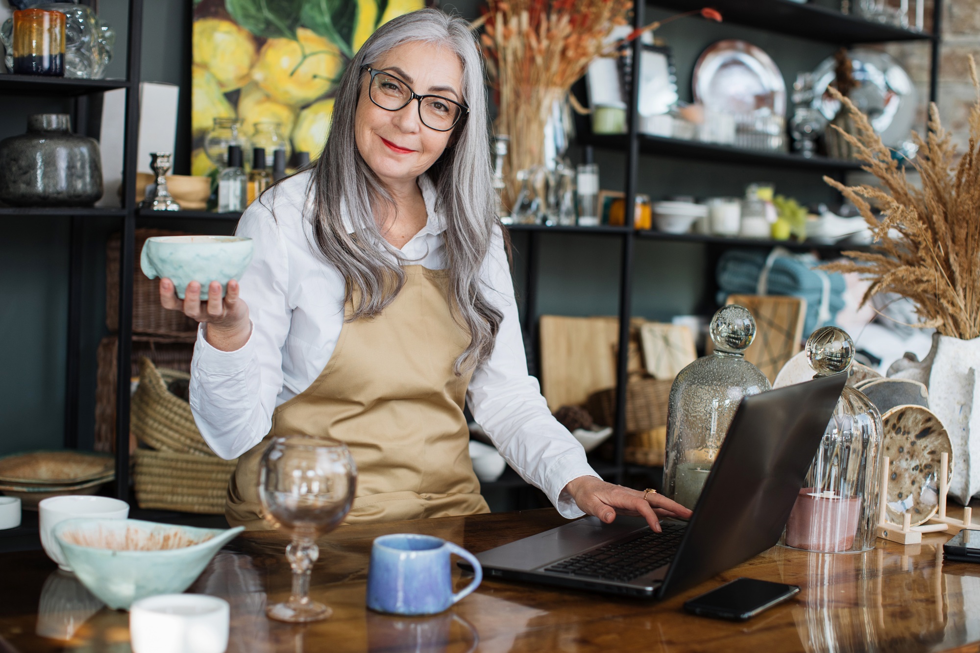 Mature woman doing inventory at decor store with laptop