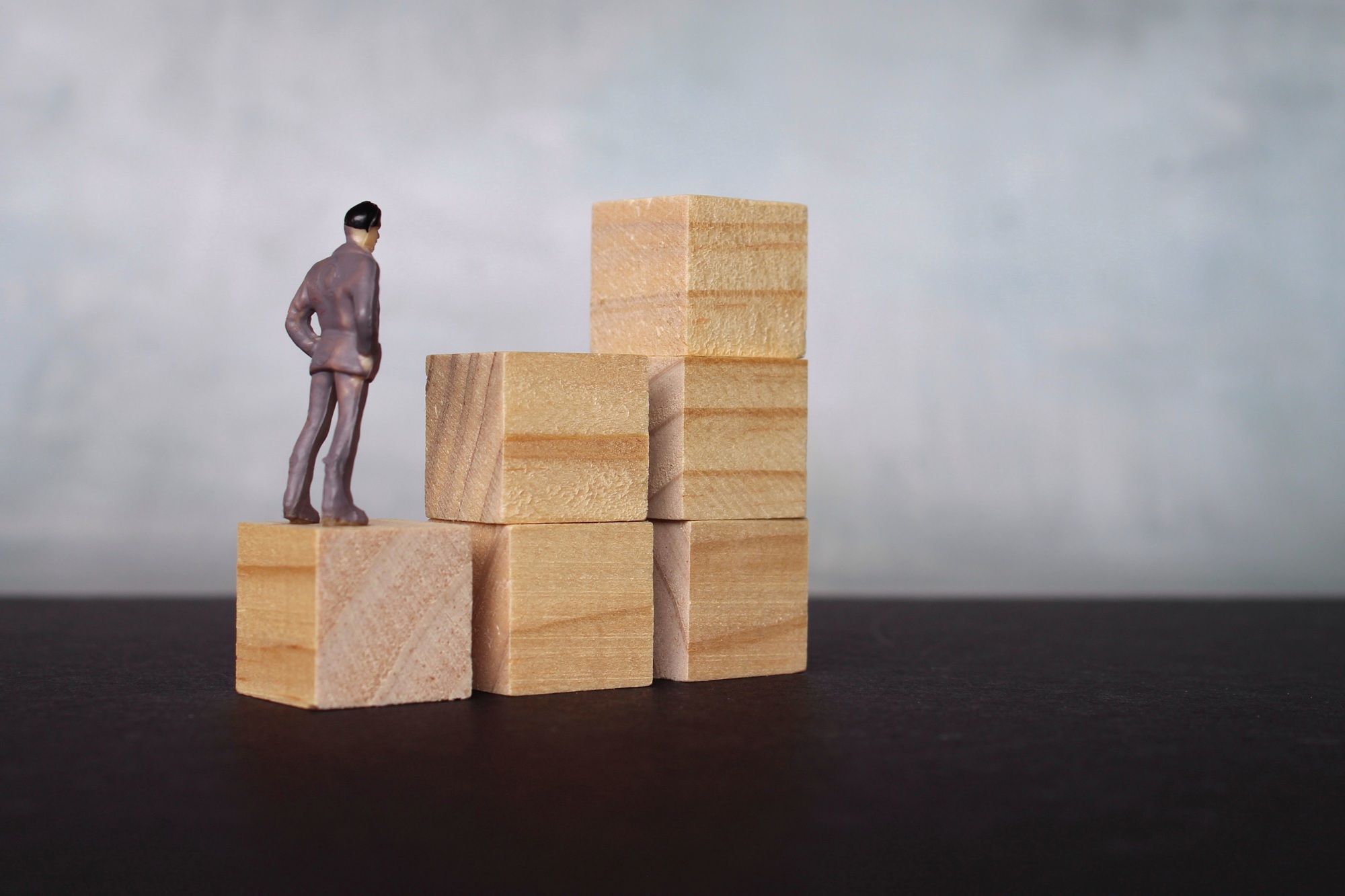 Miniature man looking at wooden step stair