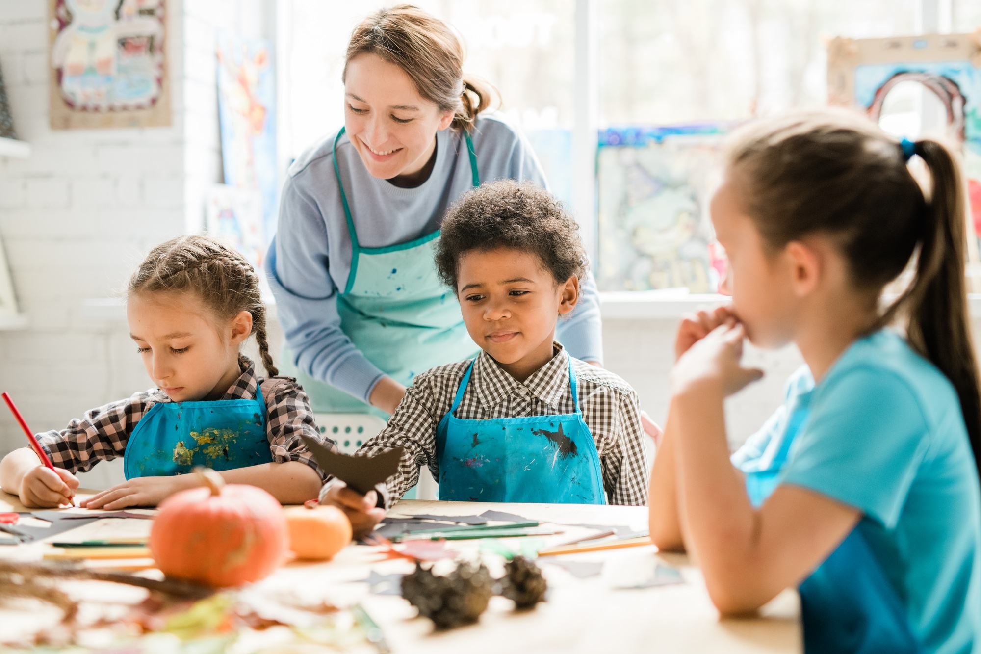 Multicultural schoolkids in aprons sharing their ideas of handmade decorations