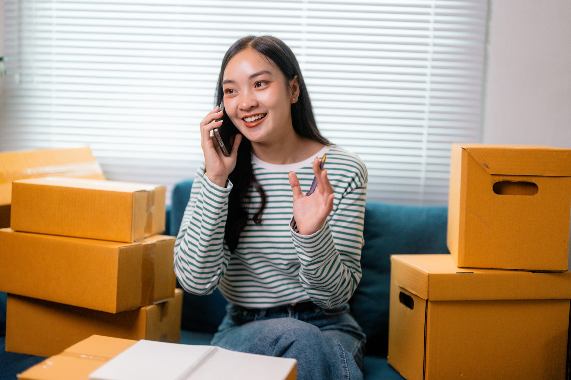 Online seller managing orders on smartphone and preparing packages for shipping