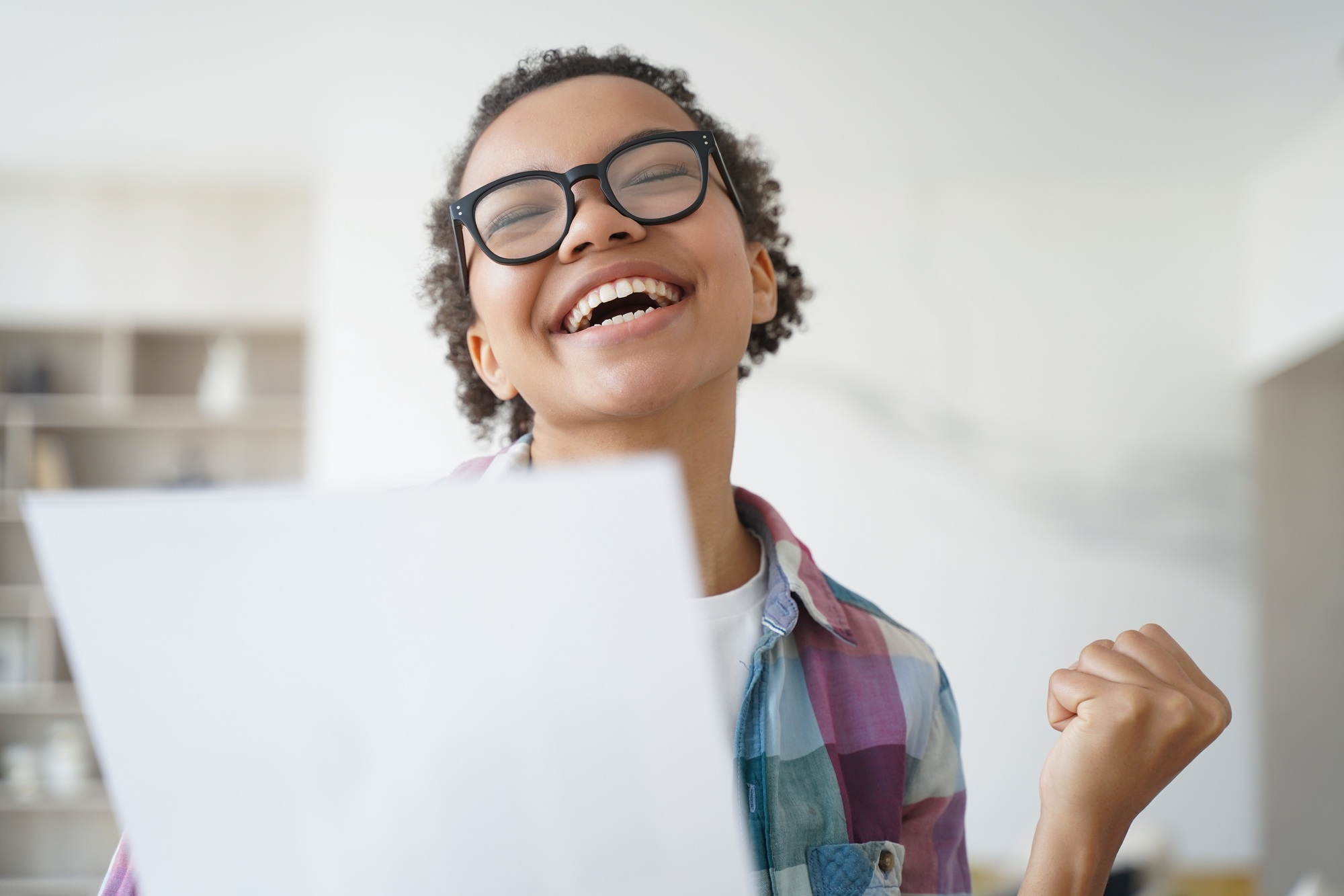 Overjoyed african american girl holds letter from university. Goal achievement and victory concept.
