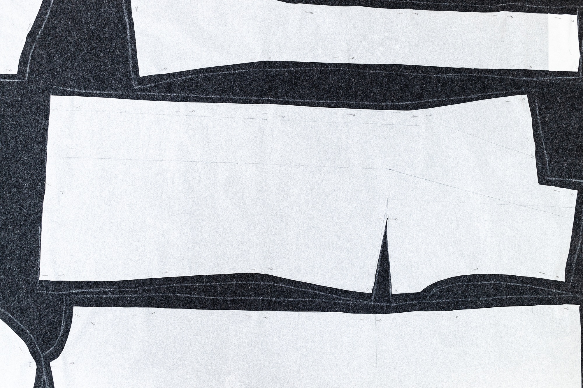 paper layout of sewing patterns on dark fabric