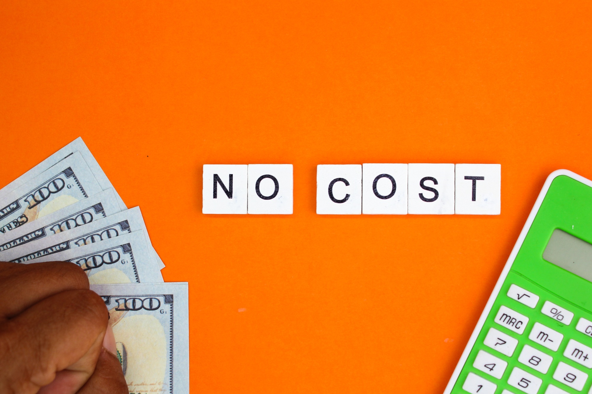 paper money, calculator and alphabet letters with the word no cost.