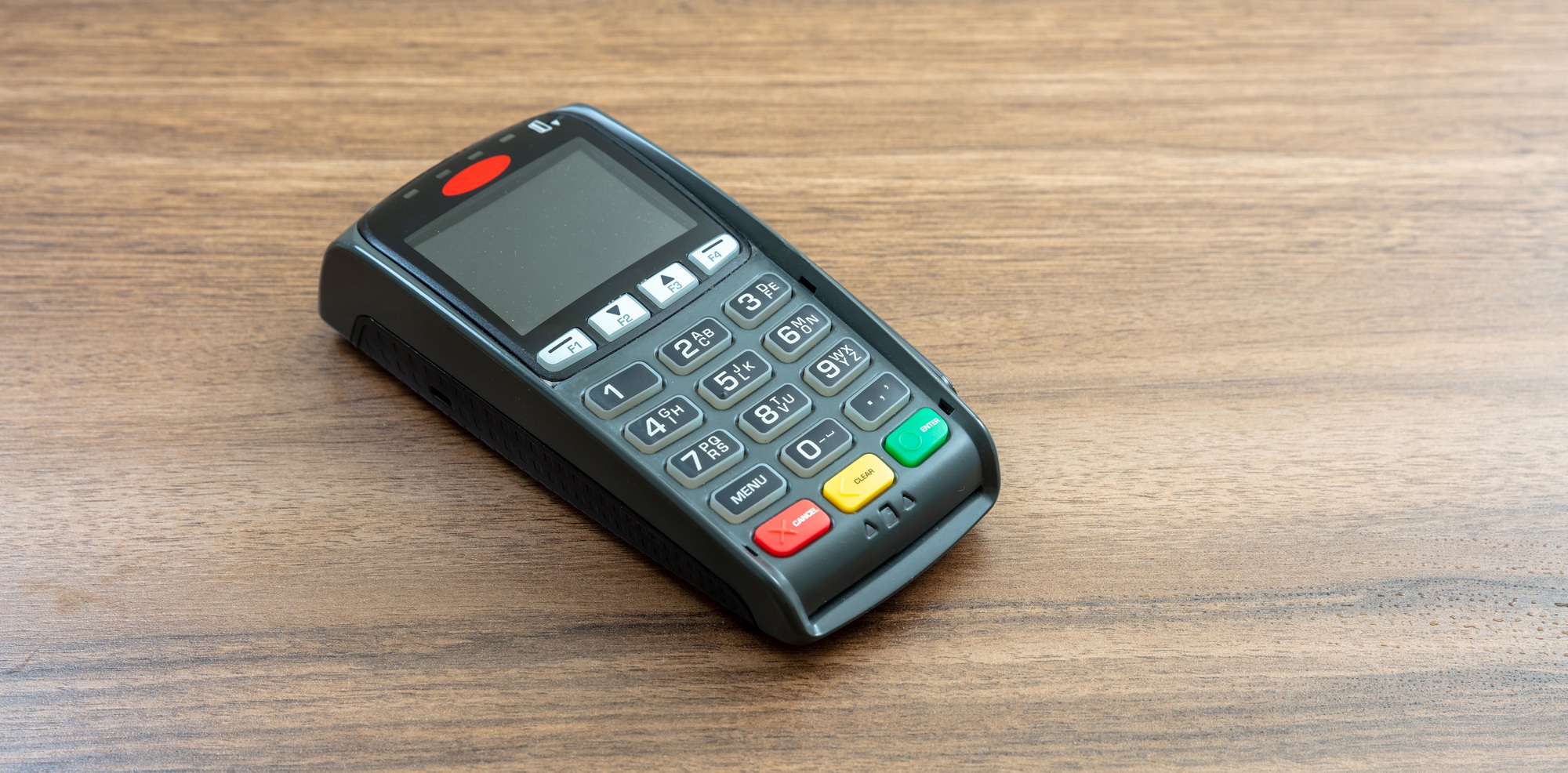 Payment machine, POS terminal on wooden background.