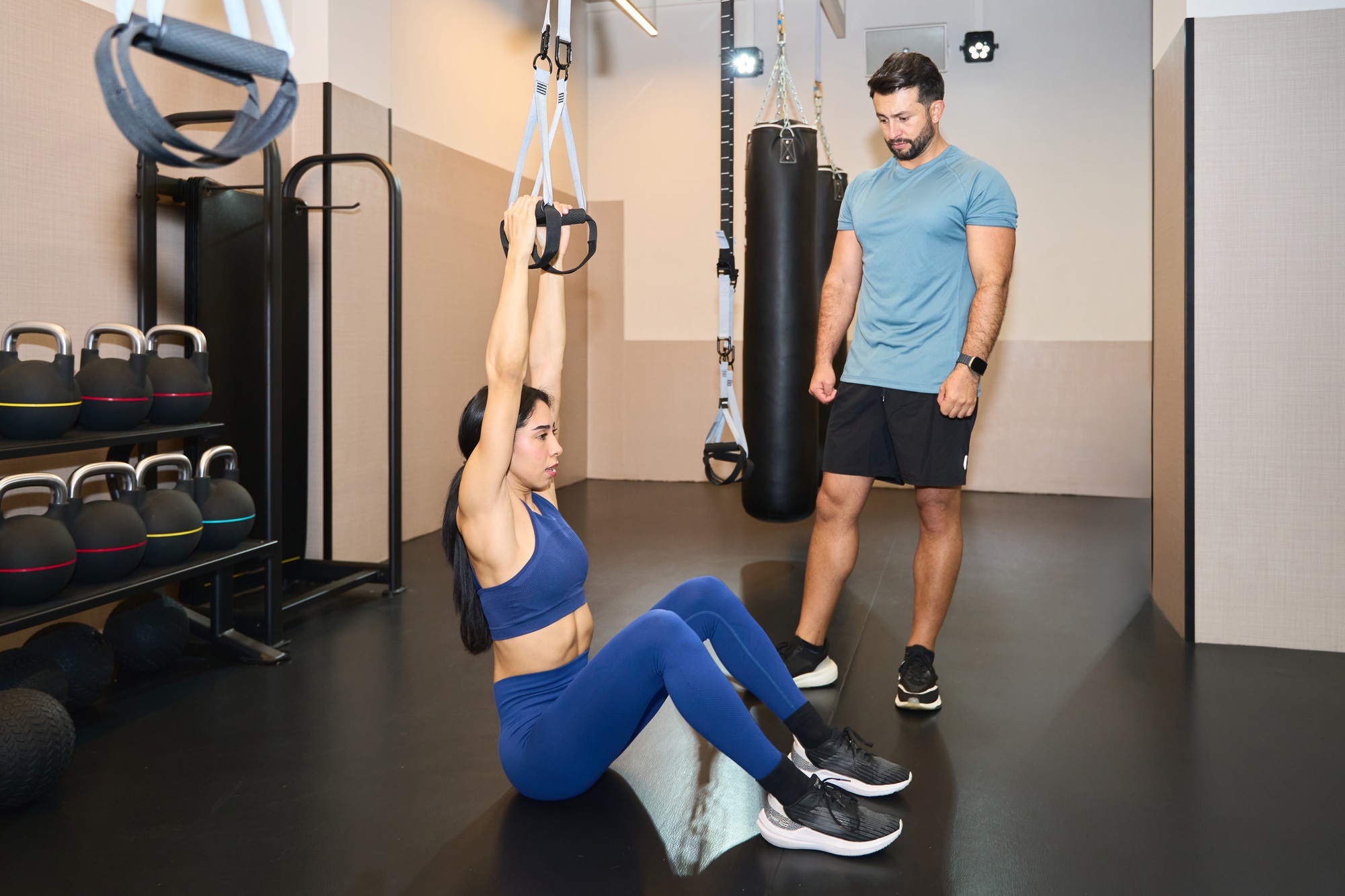 Personal trainer guiding woman in suspension training