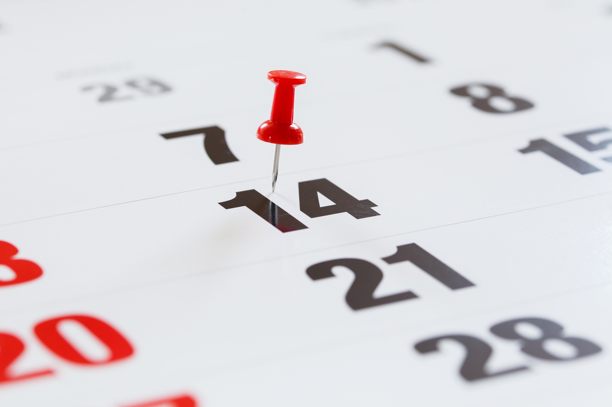 Pin pushed on a calendar concept for an important day.