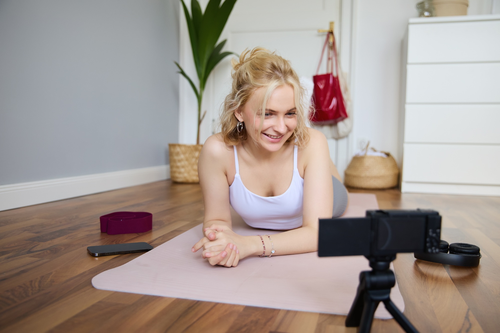 Portrait of young fitness instructor, vlogger creating content at home, doing workout and record