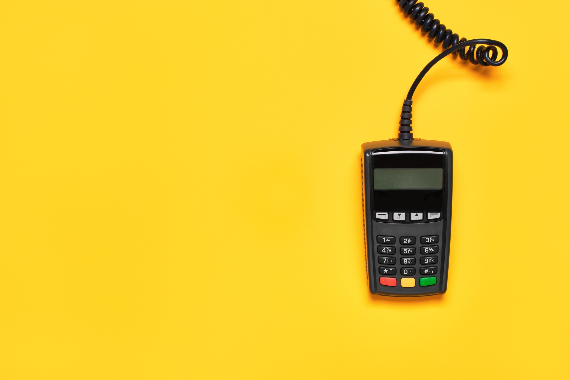 POS payment terminal on yellow background. Minimal financial service flat lay, copy space.
