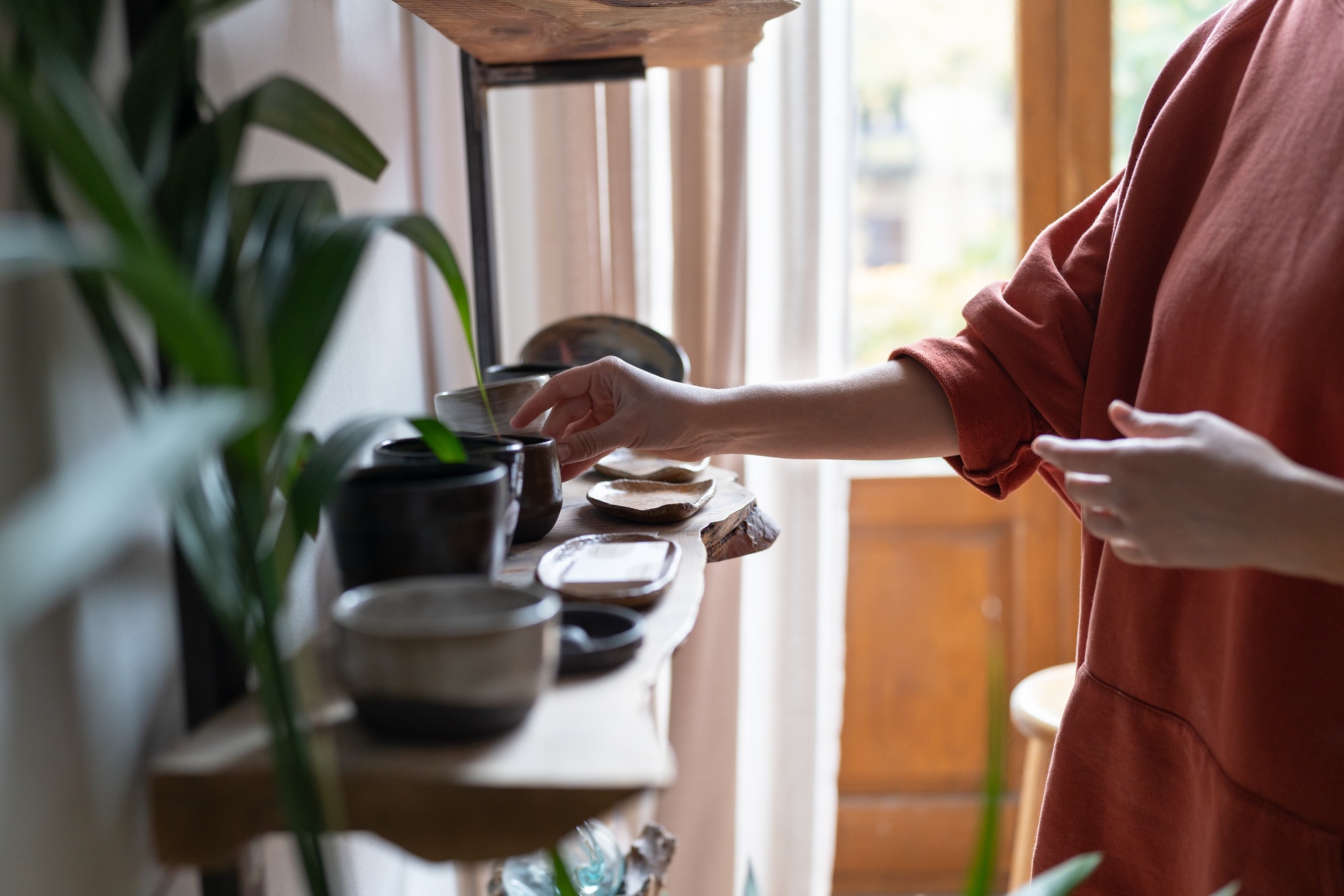 Pottery business owner arranging handmade ceramic products on shelf