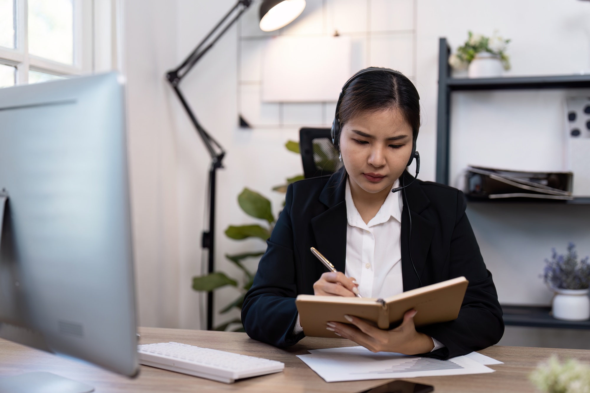Professional Businesswoman Working in Modern Office with Headset and Notebook for Effective