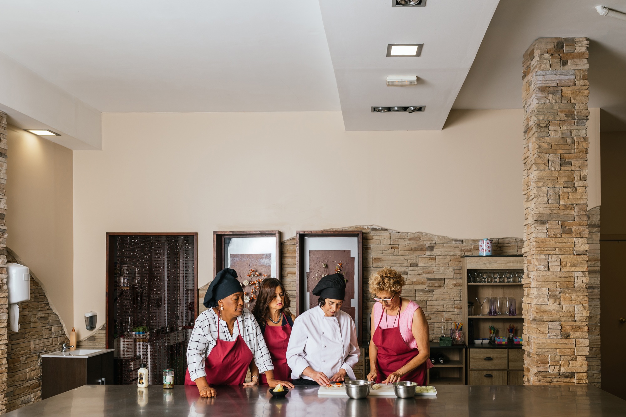 Professional chef teaching cooking course to students in restaurant kitchen