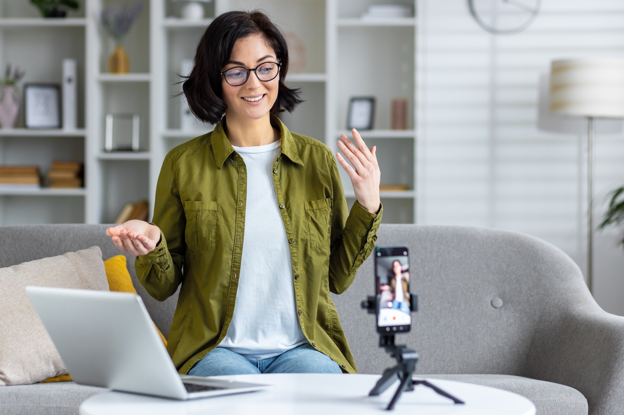 Professional woman creating content for online audience with smartphone and laptop