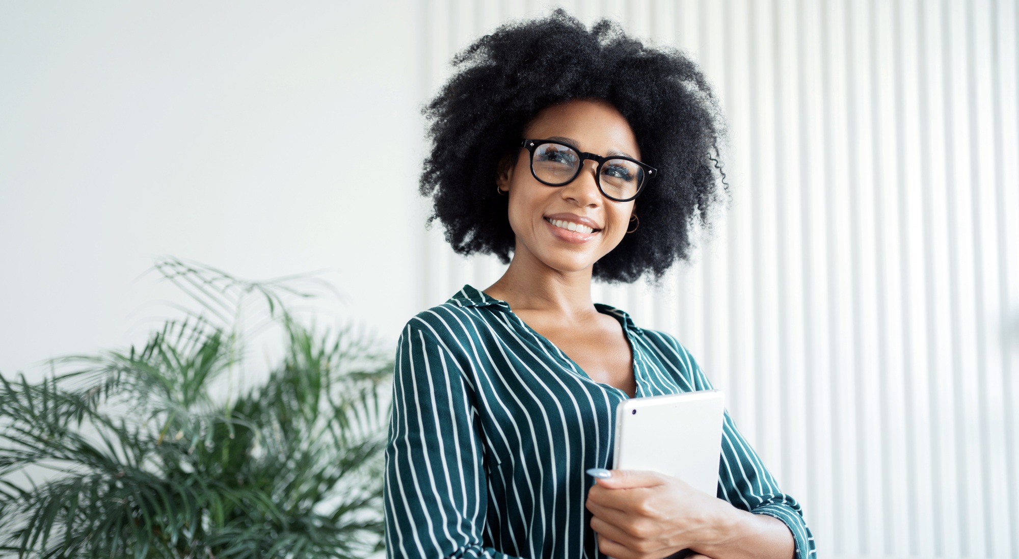 Professional woman with a tablet, confident in a modern office setting, exuding leadership