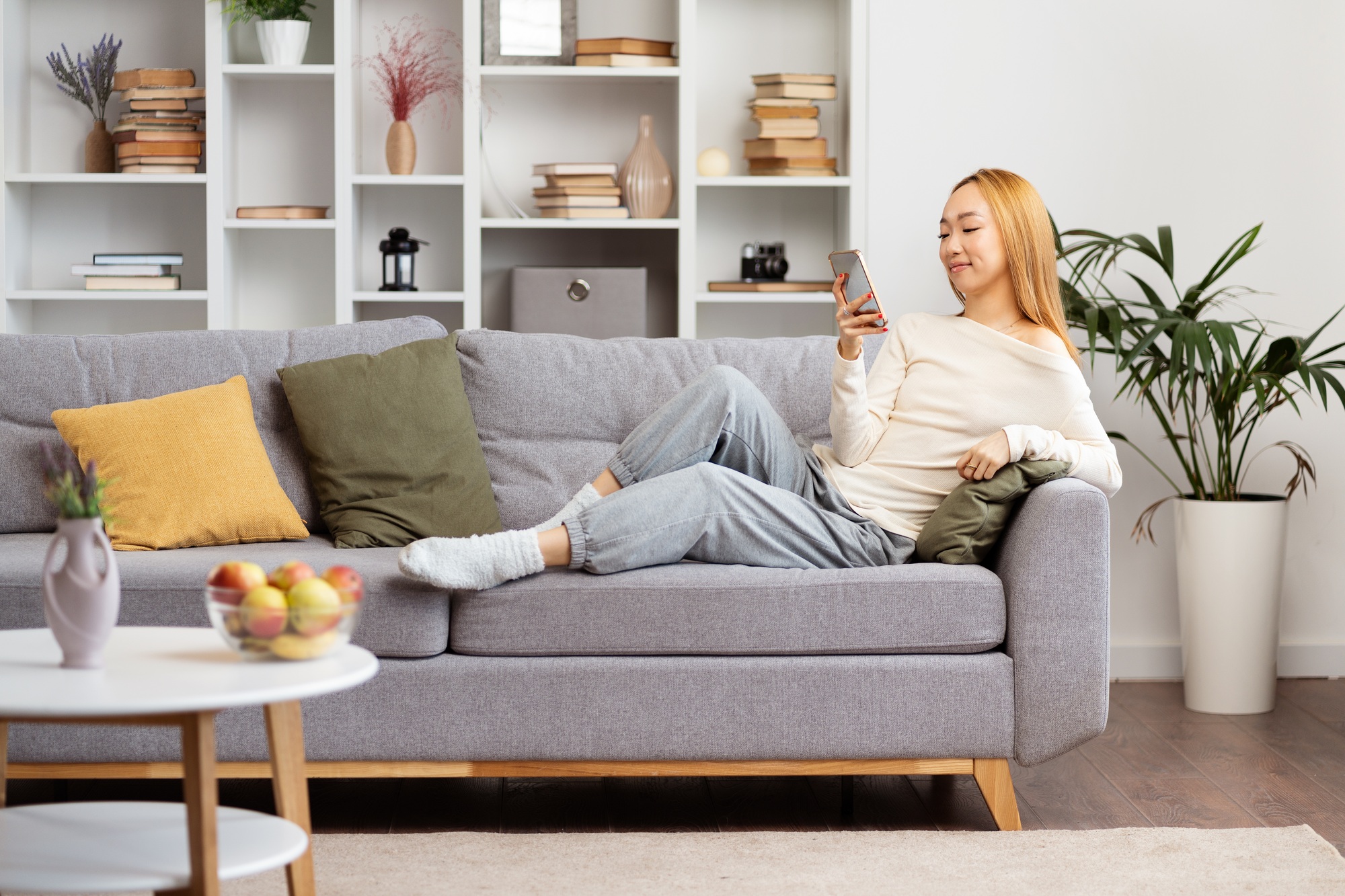 Relaxed Young Woman Enjoying Social Media On Phone At Home