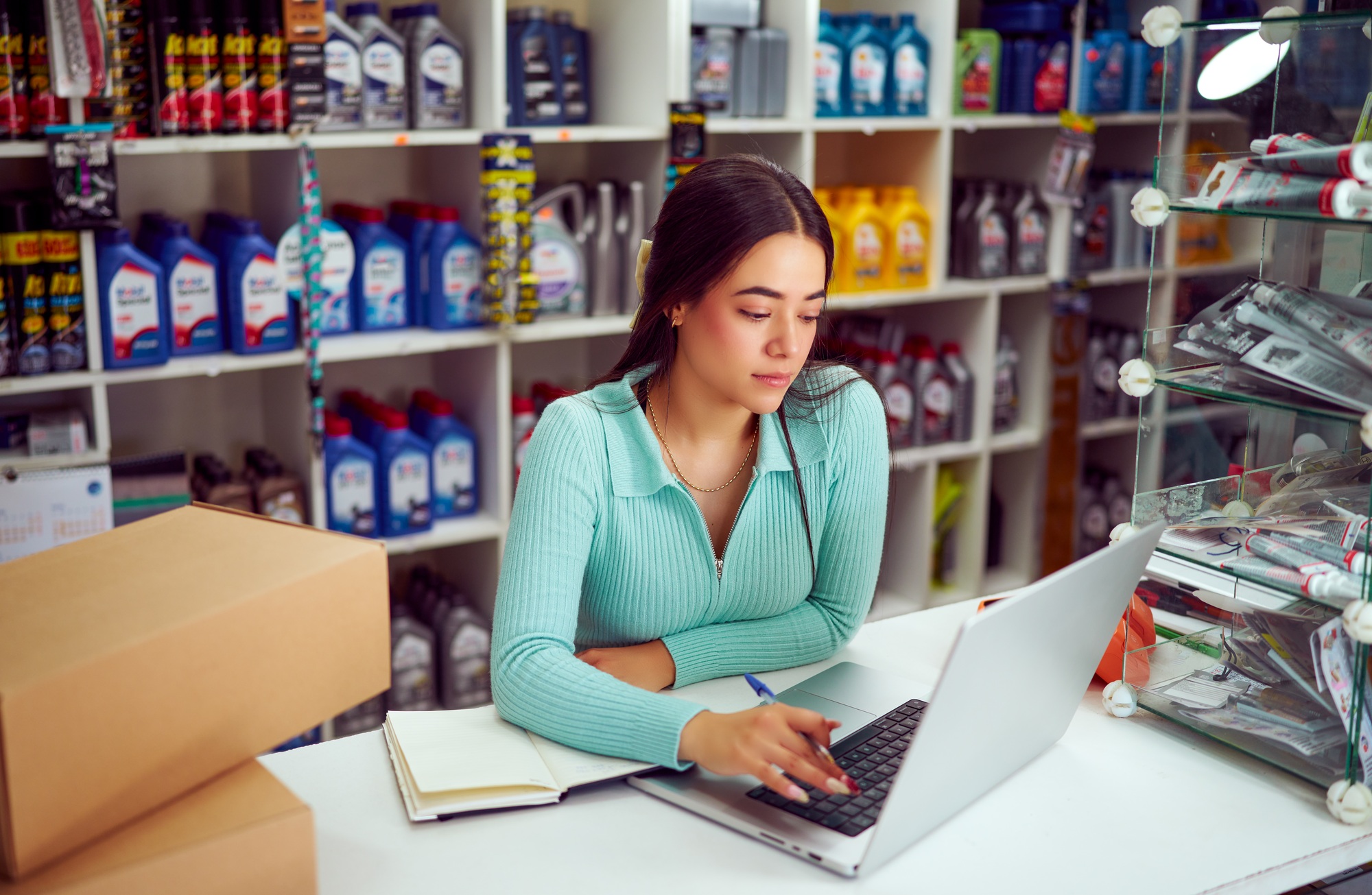 Saleswoman working on laptop in auto parts store managing inventory