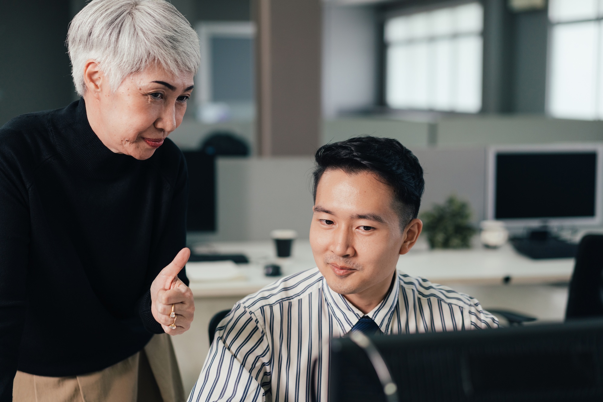 Senior female manager showing thumb up to praise employee performance