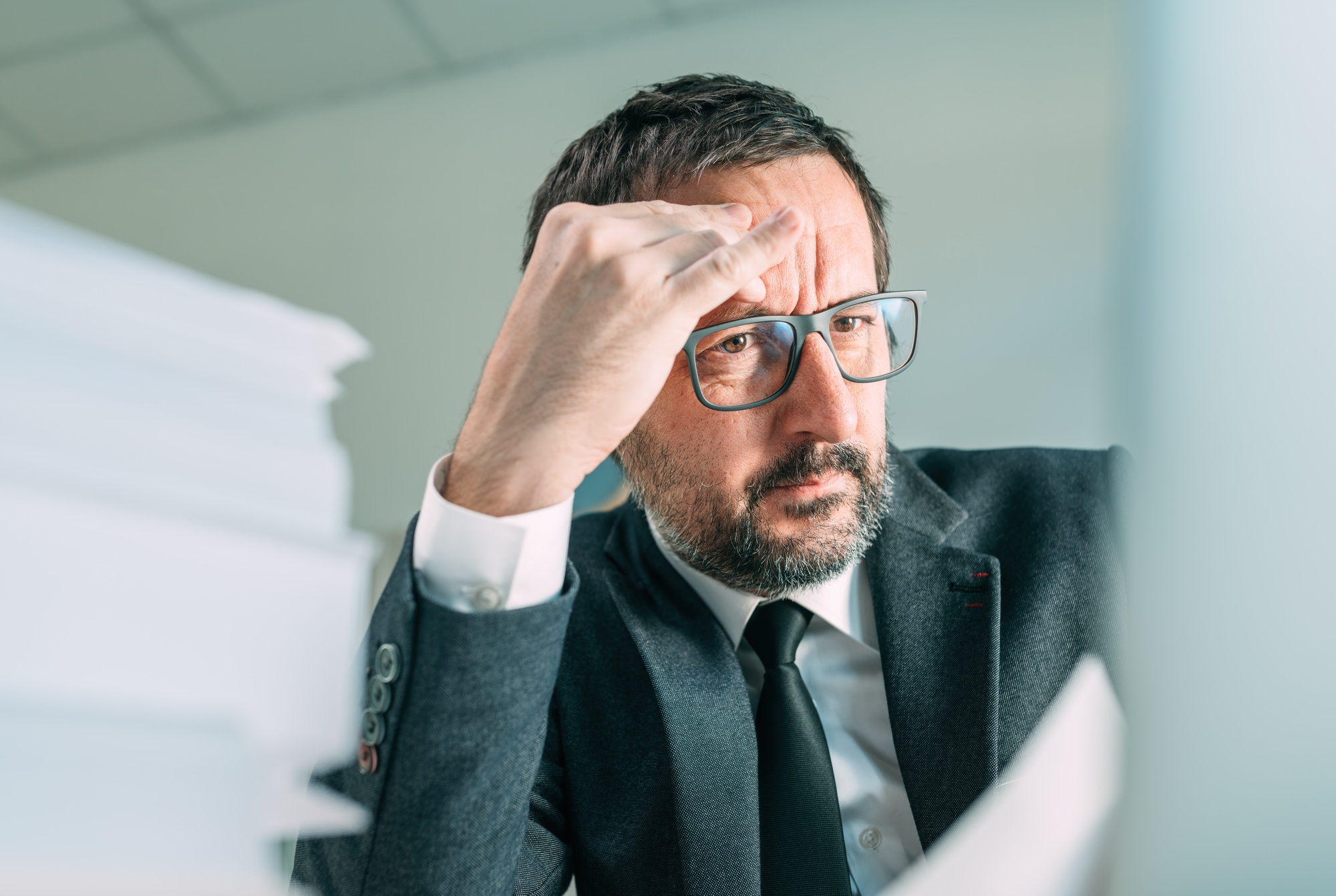 Serious business situation causing headache in office life, worried businessman looking at laptop