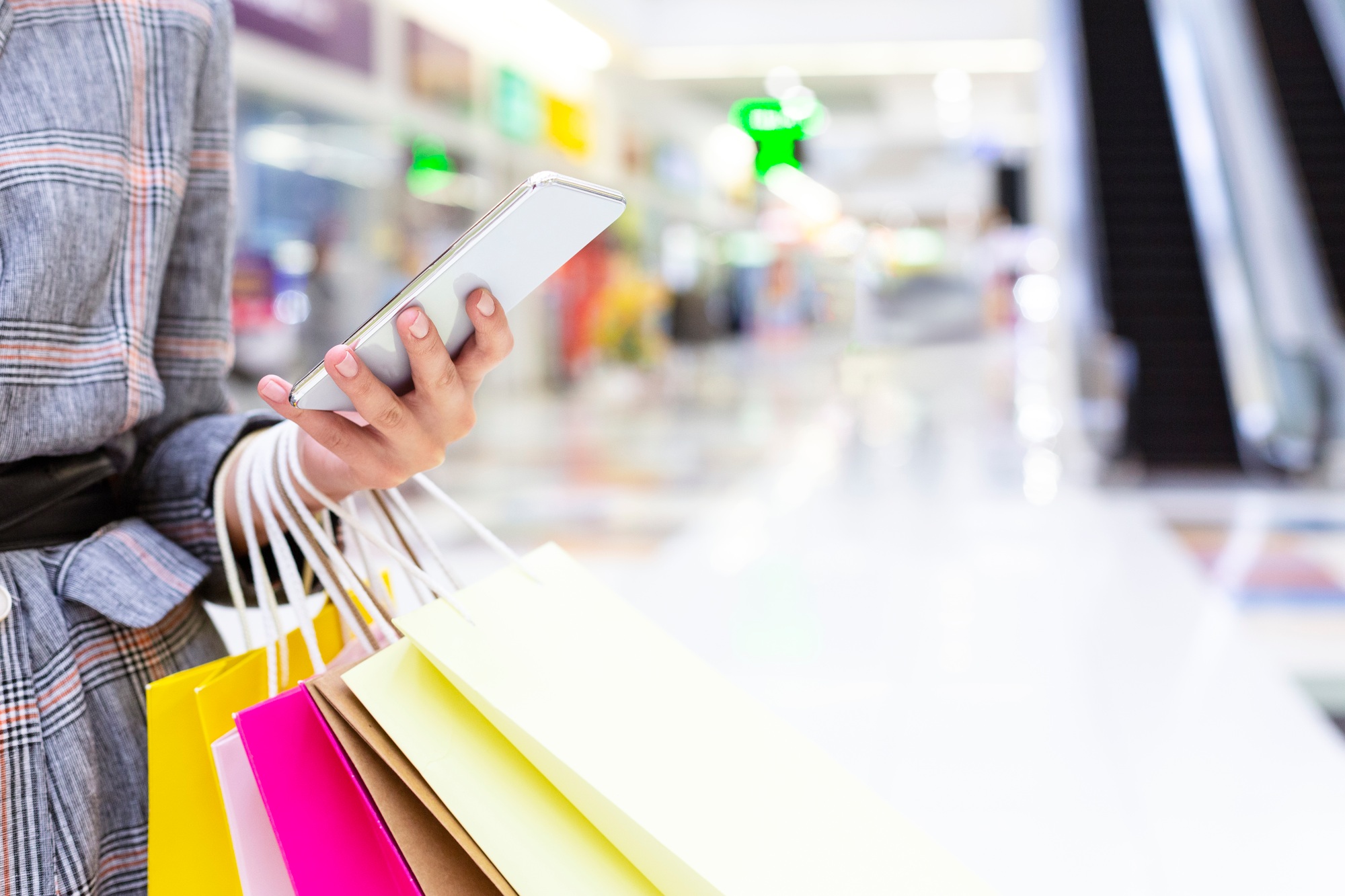 Shopping concept. Woman using smartphone in big mall