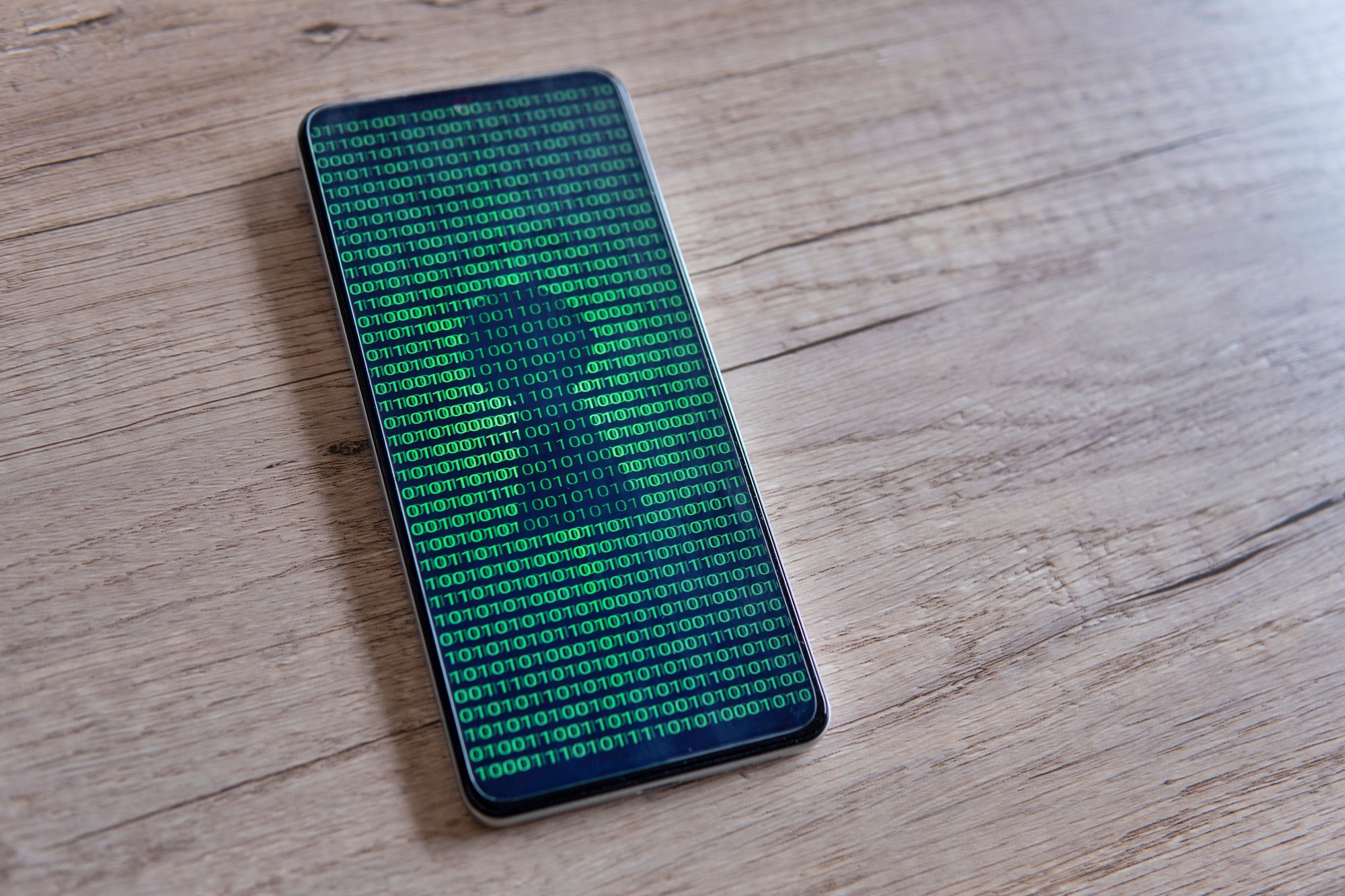 Smartphone with glowing binary code and keyhole on the screen.