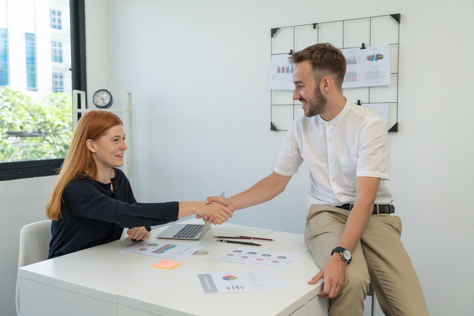 Smiling businessman handshake businesswoman colleague after discussing agreement business strategy
