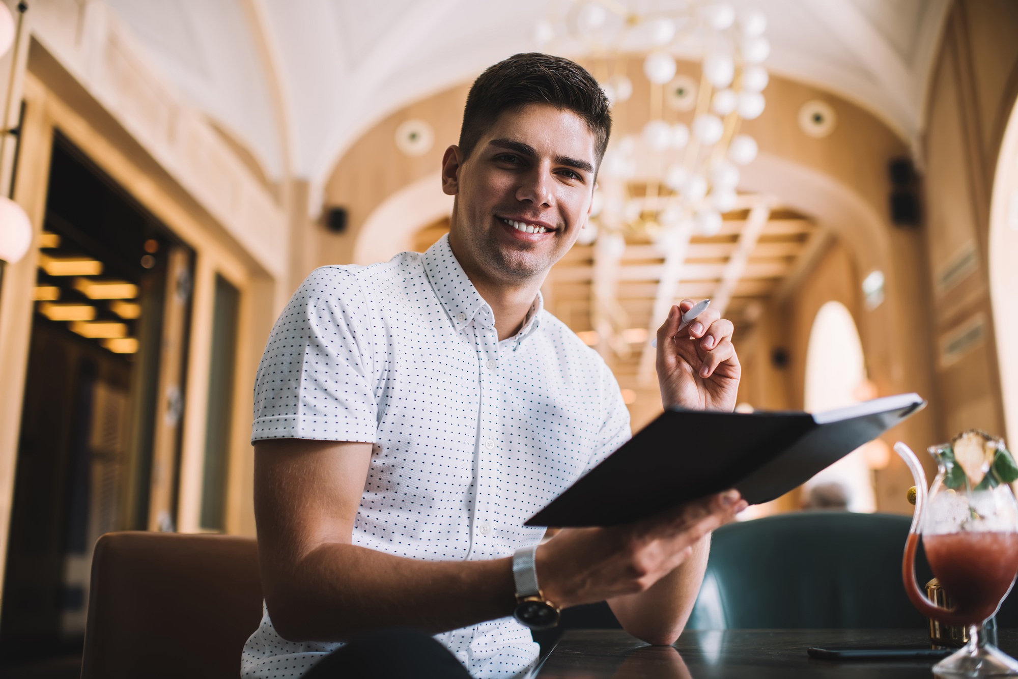 Smiling guy spending time on noting goals and targets in personal planner