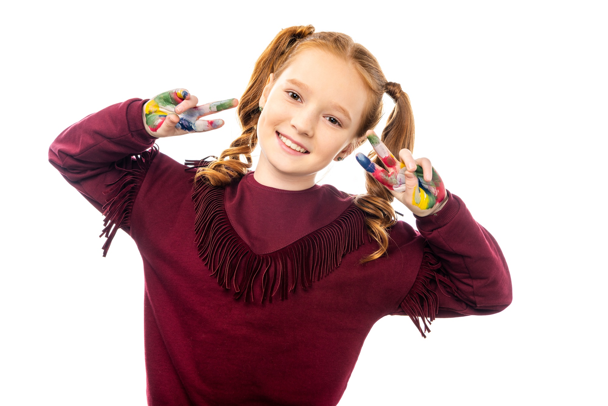 smiling schoolgirl looking at camera and showing peace signs with hands painted in colorful paints