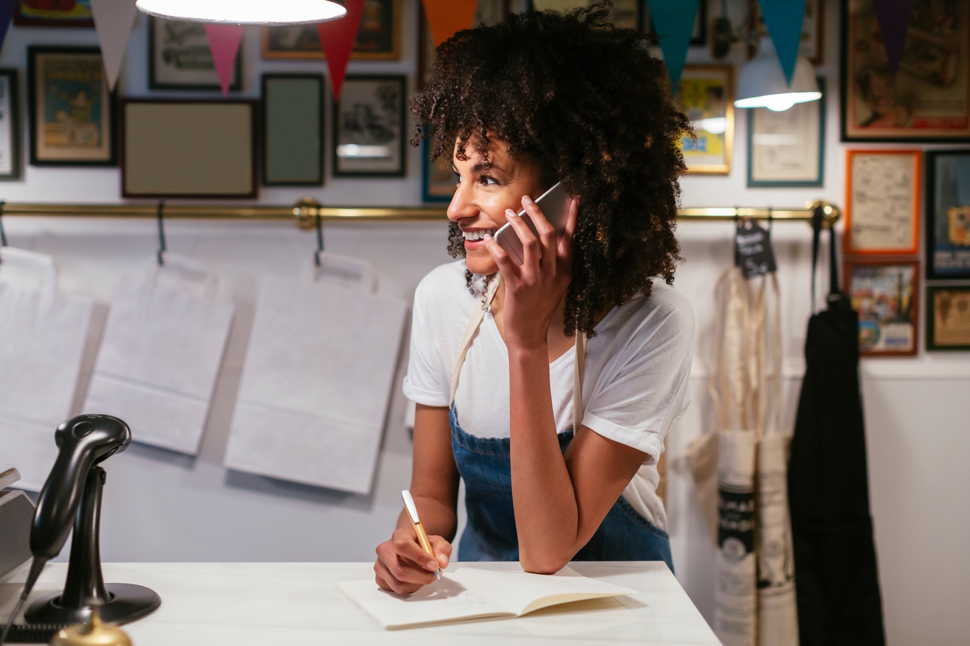 Smiling woman on the phone in a store taking notes