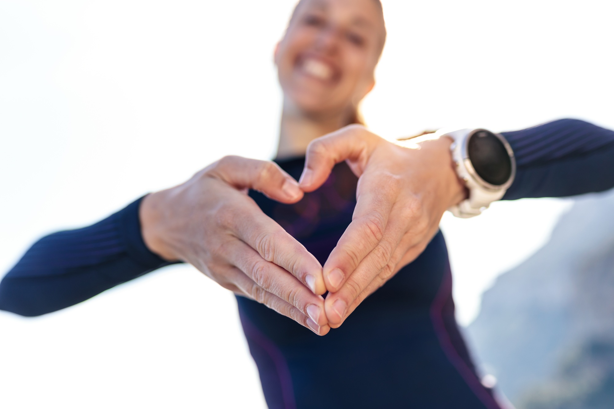 Sporty young woman making heart shape with hands while posing to